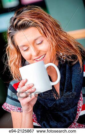 A 27 year old brunette woman sitting at an outdoor cafe and holding a white mug of hot chocolate looking down from the camera. View Large Photo Image Stock Photo - A 27 year old brunette woman sitting at an outdoor cafe and holding a white mug of hot chocolate looking down from the camera.. Fotosearch