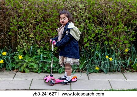 Stock Image - A Child Playing On Her Scooter, Sussex, UK.. Fotosearch