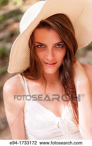 A happy 20 year old brunette woman wearing a white top and a floppy straw hat in a forest setting looking directly at the camera. View Large Photo Image Stock Image - A happy 20 year old brunette woman wearing a white top and a floppy straw hat in a forest setting looking directly at the camera.. Fotosearch