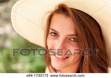 A happy 20 year old brunette woman wearing a white top and a floppy straw hat in a forest setting looking directly at the camera. View Large Photo Image Stock Image - A happy 20 year old brunette woman wearing a white top and a floppy straw hat in a forest setting looking directly at the camera.. Fotosearch