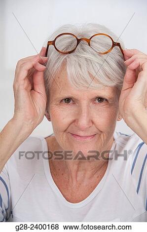 Stock Photo - Beautiful senior woman putting her glasses on her head. Fotosearch