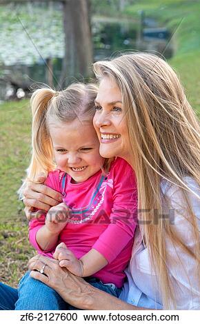 Stock Image - beautiful young mother and daughter snuggling and having fun outside in a park.. Fotosearch