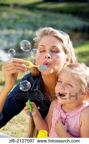 beautiful young mother and daughter blowing bubbles and snuggling outside in a park. View Large Photo Image Stock Photo - beautiful young mother and daughter blowing bubbles and snuggling outside in a park.. Fotosearch