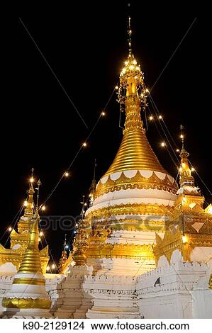 Decorative figures and gold at the pagoda of Wat Jong Kham, Mae Hong Son with the pond and the mountains in the background, Thailand, Southeast Asia. View Large Photo Image Picture - Decorative figures and gold at the pagoda of Wat Jong Kham, Mae Hong Son with the pond and the mountains in the background, Thailand, Southeast Asia.. Fotosearch