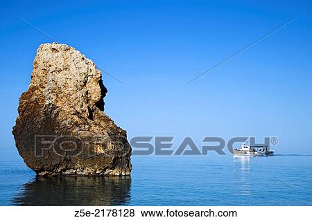 Fishing boat passes a rock at the Aegean coast of the Pelion Peninsula Thessaly, Greece View Large Photo Image Stock Photo - Fishing boat passes a rock at the Aegean coast of the Pelion Peninsula Thessaly, Greece. Fotosearch