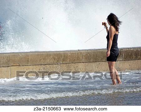 Girl making pictures of the high waves in stormy weather, located on the Malecón in Havana, Cuba. View Large Photo Image Stock Image - Girl making pictures of the high waves in stormy weather, located on the Malecón in Havana, Cuba.. Fotosearch