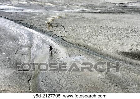 Lonely man walking barefoot in shallow waters around Mont Saint-Michel, Normandy, France. View Large Photo Image Stock Photography - Lonely man walking barefoot in shallow waters around Mont Saint-Michel, Normandy, France.. Fotosearch