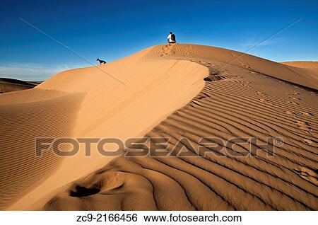 Man and dog on Sahara desert sand dunes, Erg Lihoudi, M´Hamid, Draa Valley, Morocco. View Large Photo Image Stock Photograph - Man and dog on Sahara desert sand dunes, Erg Lihoudi, M´Hamid, Draa Valley, Morocco.. Fotosearch