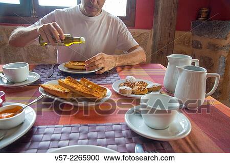 Man pouring olive oil on toasts at breakfast. View Large Photo Image Stock Image - Man pouring olive oil on toasts at breakfast.. Fotosearch