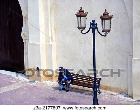 Man sitting on a bench near the Koutoubia Mosque in the old town of Marrakech, Morocco. View Large Photo Image Stock Photo - Man sitting on a bench near the Koutoubia Mosque in the old town of Marrakech, Morocco.. Fotosearch