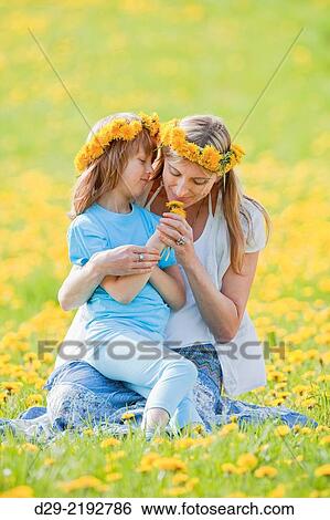 Stock Photograph - mother and son picking flowers at dandelions field in spring.. Fotosearch