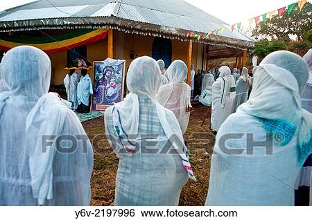 Stock Photograph - Orthodox christian women participating at a sunday mass. In the background, two priests are standing near a painting of Jesus and Mary. Bahir Dar, Amhara state, Ethiopia.. Fotosearch