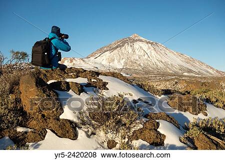 Stock Photo - Photographer at sunrise in snow covered Teide National Park on Tenerife, Canary Islands, Spain.. Fotosearch