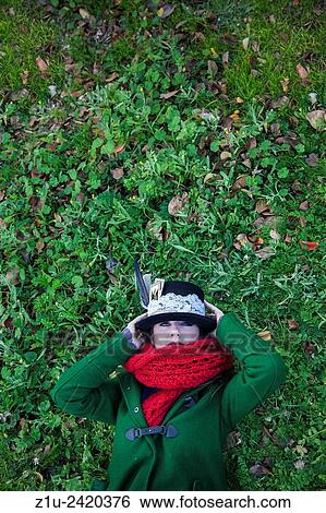 Stock Photograph - Portrait. Girl with hat lying on the grass. Inspiration Alice in Wonderland.. Fotosearch