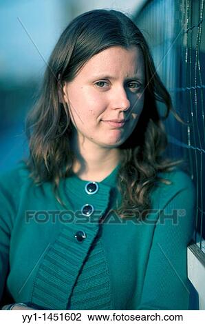 Stock Image - Portrait of a young woman near a fence.. Fotosearch