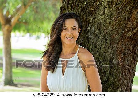 Smiling woman standing by a tree in Balboa park, San Diego, California. View Large Photo Image Picture - Smiling woman standing by a tree in Balboa park, San Diego, California.. Fotosearch