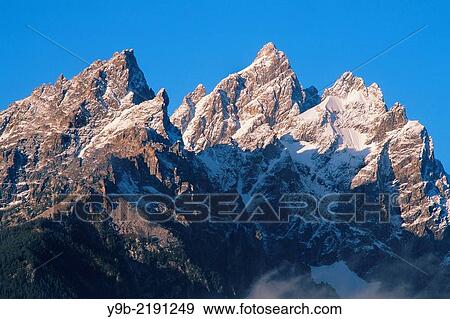 Sunrise on the Cathedral Group of the Teton Range with fresh autumn snow; Grand Teton rises in the center, Grand Teton National Park, Wyoming, USA. View Large Photo Image Stock Photo - Sunrise on the Cathedral Group of the Teton Range with fresh autumn snow; Grand Teton rises in the center, Grand Teton National Park, Wyoming, USA.. Fotosearch