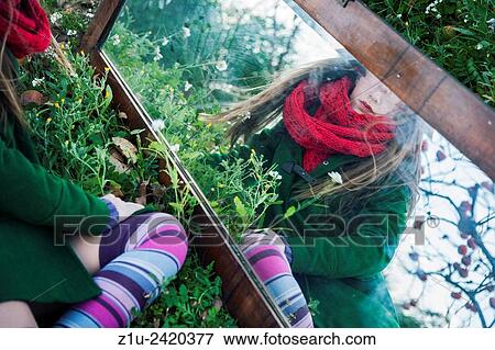 Stock Photo - The girl in the mirror. Inspiration Alice in Wonderland. Reflection.. Fotosearch