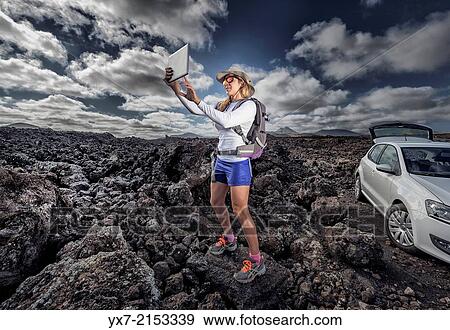 Tourist using a Tablet at Timanfaya National Park, Lanzarote, Canary Islands, Spain. View Large Photo Image Stock Photo - Tourist using a Tablet at Timanfaya National Park, Lanzarote, Canary Islands, Spain.. Fotosearch