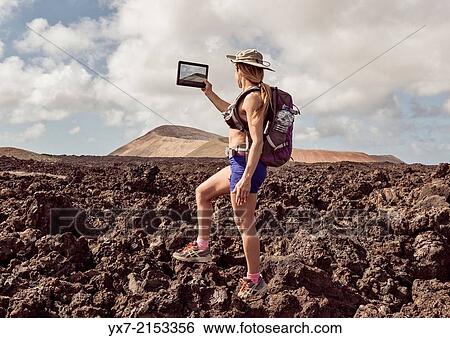 Traveler using a tablet at Timanfaya National Park, Lanzarote, Canary Islands, Spain. View Large Photo Image Stock Photograph - Traveler using a tablet at Timanfaya National Park, Lanzarote, Canary Islands, Spain.. Fotosearch
