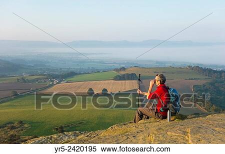 Walker on Cliff Ridge at sunrise with Roseberry Topping in distance. North York Moors, National Park, England, United Kingdom. View Large Photo Image Stock Photography - Walker on Cliff Ridge at sunrise with Roseberry Topping in distance. North York Moors, National Park, England, United Kingdom.. Fotosearch