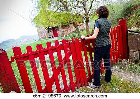 Stock Image - Woman, house and fence.. Fotosearch