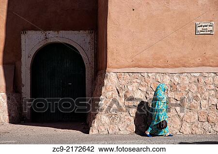 Woman in traditional moroccan niqab walking by the adobe medina wall, Tiznit, Morocco. View Large Photo Image Stock Image - Woman in traditional moroccan niqab walking by the adobe medina wall, Tiznit, Morocco.. Fotosearch