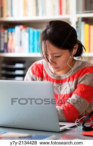 Young Asian woman in casual clothes works at the desk in her home office. View Large Photo Image Stock Photo - Young Asian woman in casual clothes works at the desk in her home office.. Fotosearch