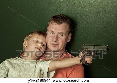 Young boy, holding a toy gun, with his father. View Large Photo Image Picture - Young boy, holding a toy gun, with his father.. Fotosearch
