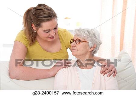 Young medical help or granddaughter holding beautiful senior woman by her shoulders, and smiling to her, at home View Large Photo Image Stock Photo - Young medical help or granddaughter holding beautiful senior woman by her shoulders, and smiling to her, at home. Fotosearch