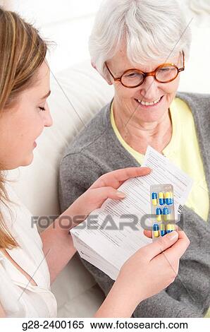 Young nurse or help or granddaughter reading prescription paper, and holding tablets, for patient or grandmother who is laughing in the background View Large Photo Image Stock Photography - Young nurse or help or granddaughter reading prescription paper, and holding tablets, for patient or grandmother who is laughing in the background. Fotosearch