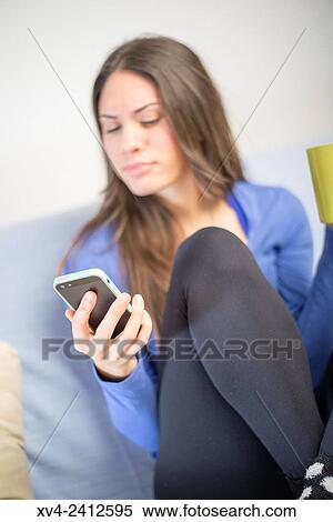 Young Woman chating on her sofa and drinking hot beverage. View Large Photo Image Stock Photography - Young Woman chating on her sofa and drinking hot beverage.. Fotosearch