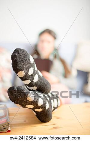Picture - Young Woman relaxing on her sofa and listening to music on her tablet with Headphones.. Fotosearch