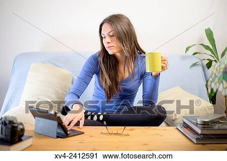 Young Woman relaxing on her sofa and drinking hot beverage. View Large Photo Image Stock Image - Young Woman relaxing on her sofa and drinking hot beverage.. Fotosearch