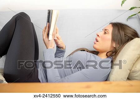 Young Woman relaxing on her sofa reading a book. View Large Photo Image Stock Image - Young Woman relaxing on her sofa reading a book.. Fotosearch