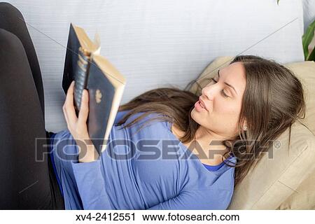 Young Woman relaxing on her sofa reading a book. View Large Photo Image Stock Image - Young Woman relaxing on her sofa reading a book.. Fotosearch