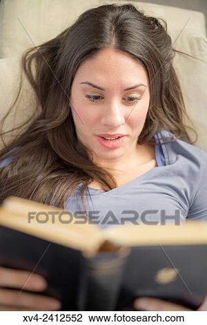 Young Woman relaxing on her sofa reading a book. View Large Photo Image Stock Image - Young Woman relaxing on her sofa reading a book.. Fotosearch