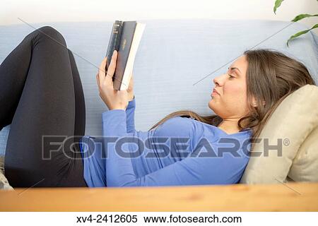 Young Woman relaxing on her sofa reading a book. View Large Photo Image Stock Photography - Young Woman relaxing on her sofa reading a book.. Fotosearch