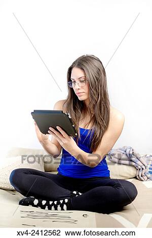 Young Woman relaxing on her sofa with her tablet. View Large Photo Image Stock Image - Young Woman relaxing on her sofa with her tablet.. Fotosearch