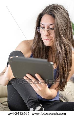 Young Woman relaxing on her sofa with her tablet. View Large Photo Image Stock Photography - Young Woman relaxing on her sofa with her tablet.. Fotosearch
