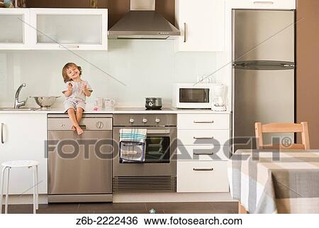 Stock Photograph - 23 moths old baby girl seated on the counter top at the kitchen.. Fotosearch