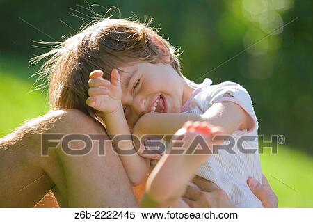 Stock Photography - 3 years old little girl laughing with her father during a summer day in the garden.. Fotosearch