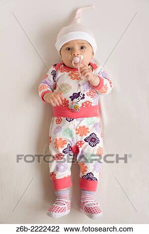 6 months Baby girl liyng on bed with pyjamas, bonnet, shoes and dummy. View Large Photo Image Stock Image - 6 months Baby girl liyng on bed with pyjamas, bonnet, shoes and dummy.. Fotosearch