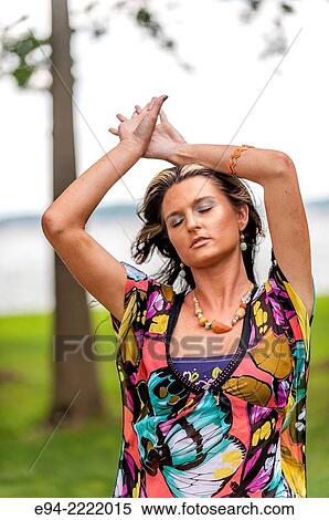 A 27 year old brunette woman in a dress with eyes closed an arms raised above her head, outdoors. View Large Photo Image Stock Photography - A 27 year old brunette woman in a dress with eyes closed an arms raised above her head, outdoors.. Fotosearch