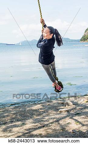 Stock Image - a girl, 12, swings on a rope on Saturna Island, BC, Canada.. Fotosearch