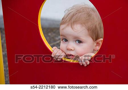 A toddler looks through a circular window at a park. View Large Photo Image Stock Image - A toddler looks through a circular window at a park.. Fotosearch