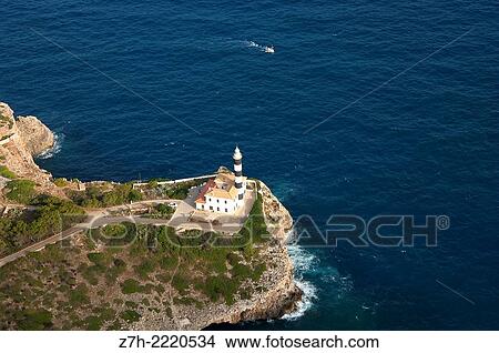 Picture - Aerial view of a lighthouse with a small boat approaching Port de Soller (Mallorca).. Fotosearch