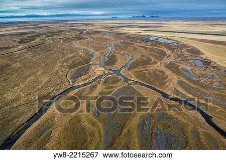 Stock Photo - Aerial view of rivers, earth mounds and farmland, Westmand Islands in the background, Iceland.. Fotosearch