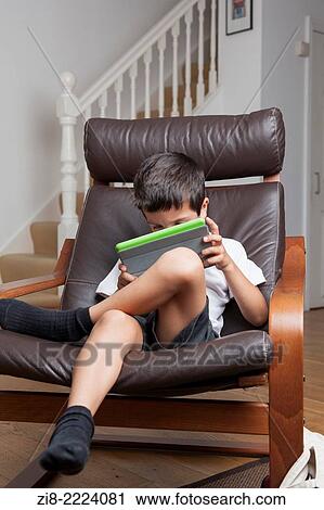 Boy plays on a tablet at home. View Large Photo Image Stock Image - Boy plays on a tablet at home.. Fotosearch
