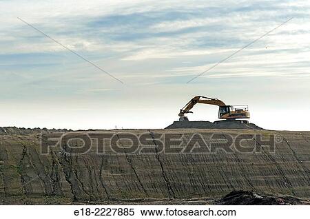 Stock Photography - Canada, BC, Delta. Excavator silhouetted against sky on construction site preload, River Road.. Fotosearch